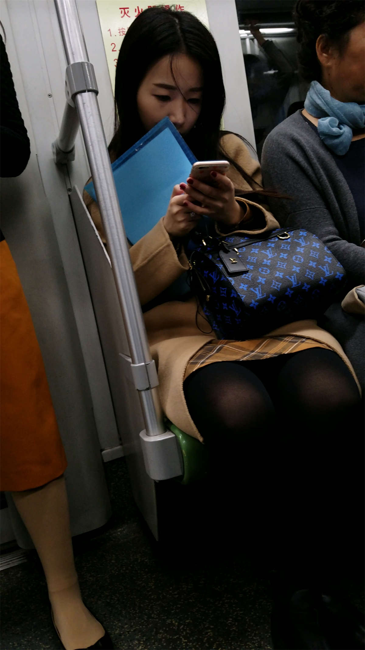地铁玩手机的米色外套黑色丝袜OL美眉-日更街拍